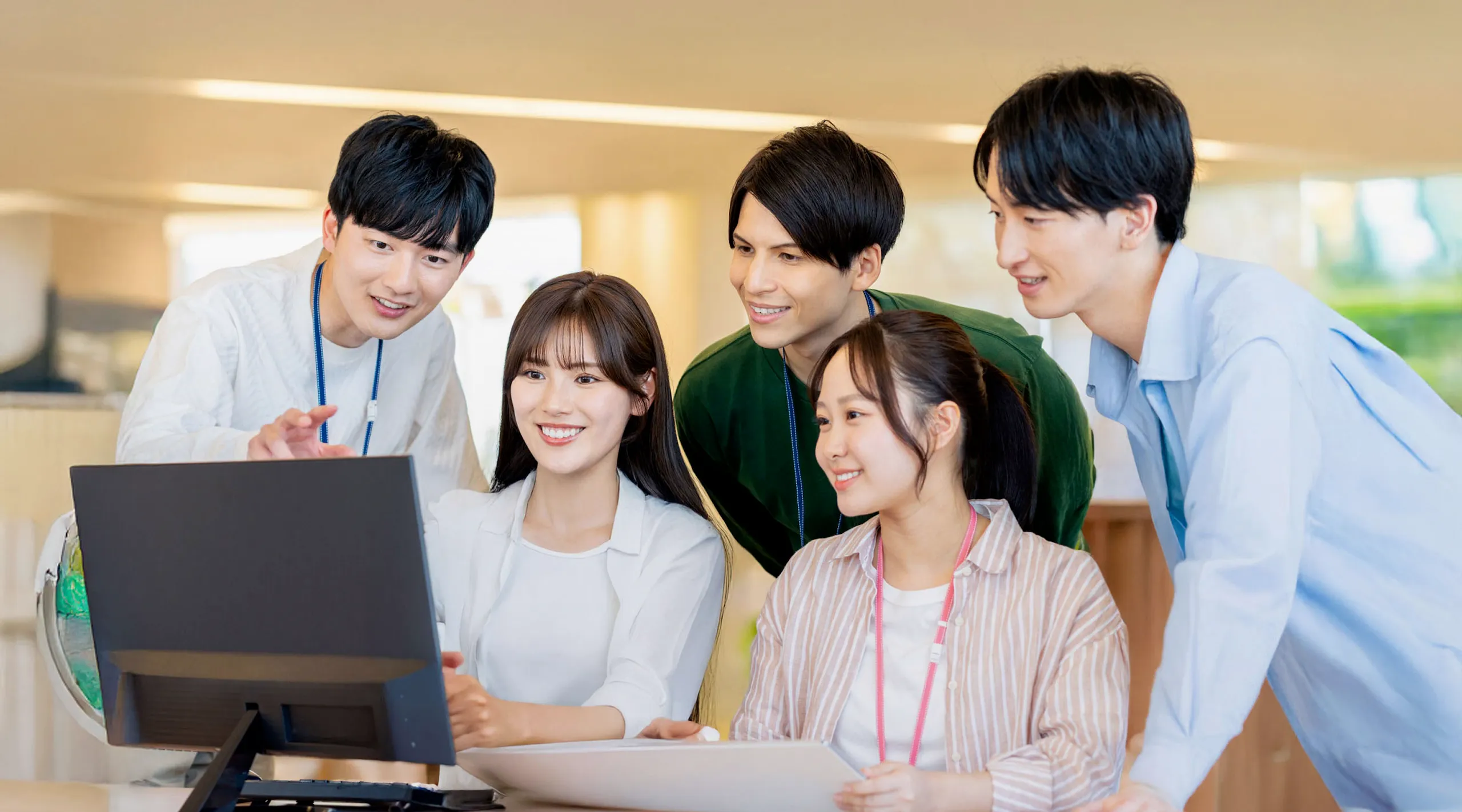 PCの前に集まる会社の仲間たちの様子