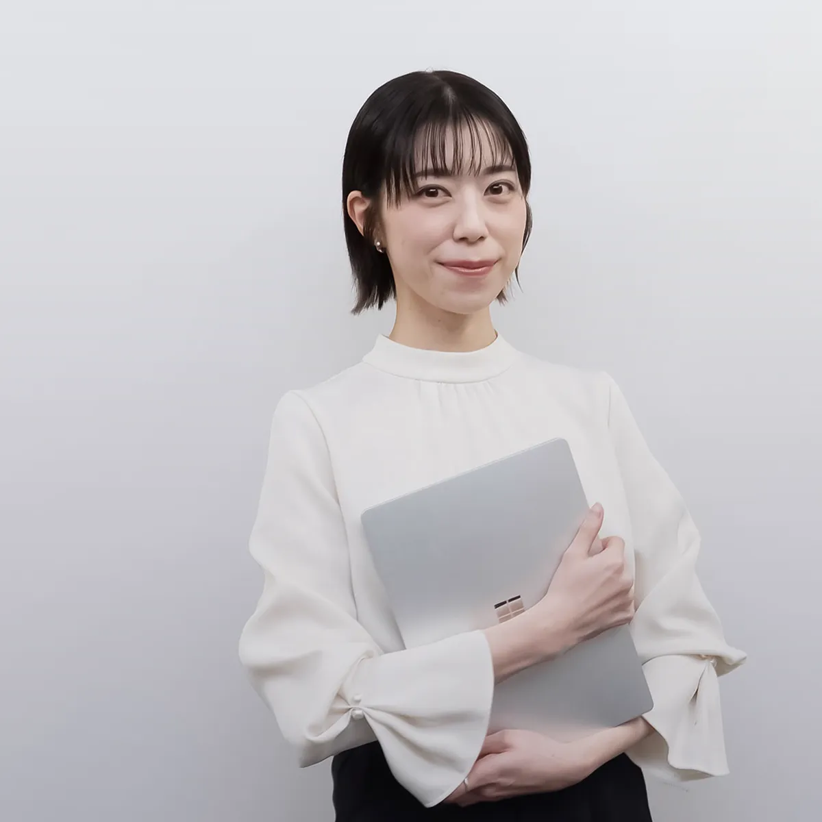 ノートPCを抱えて立つ女性社員